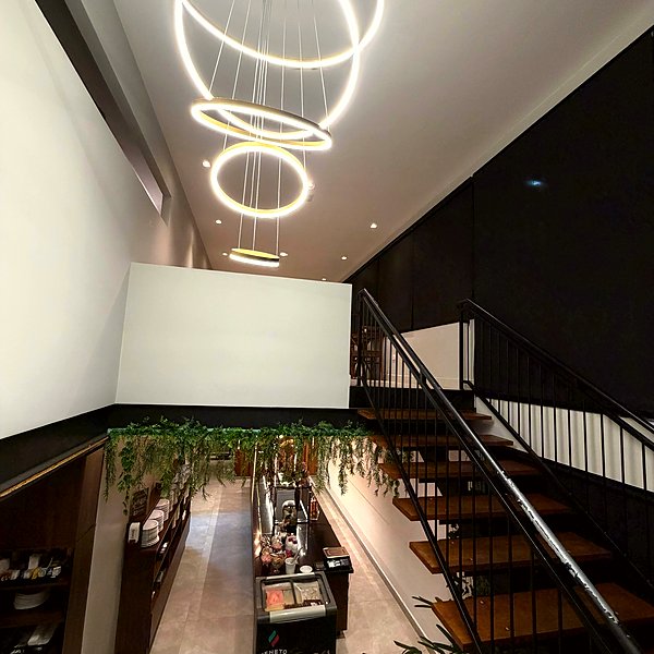 Lustre circular de LED sobre escadaria com plantas decorativas na Gentil Panificadora